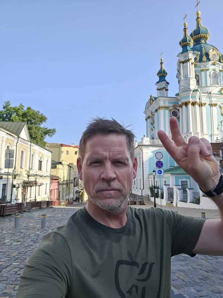 Чоловік показує жест миру на фоні церкви в Києві